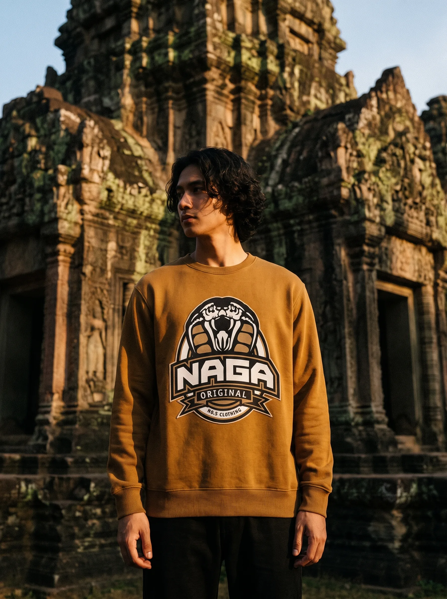 Model in a tan Naga Original crewneck with real cobra logo at an Angkor temple